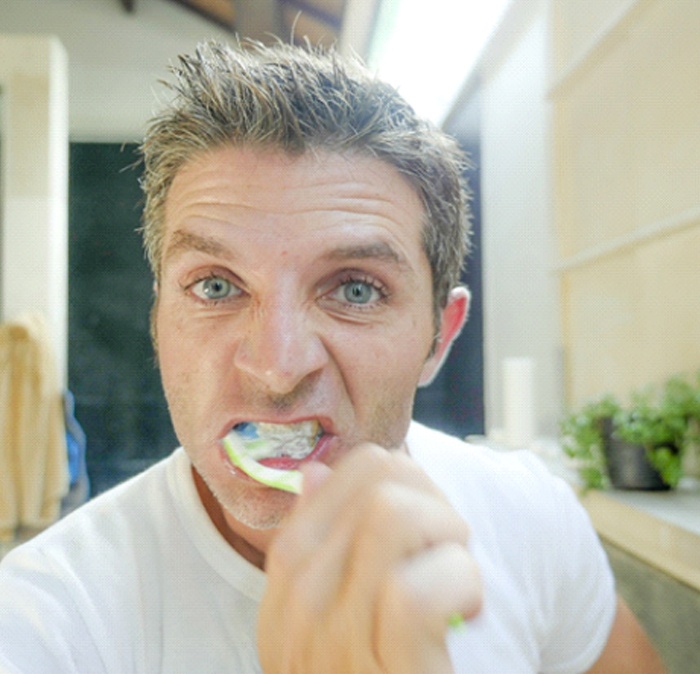 Man brushing teeth after getting dental implants in Houston