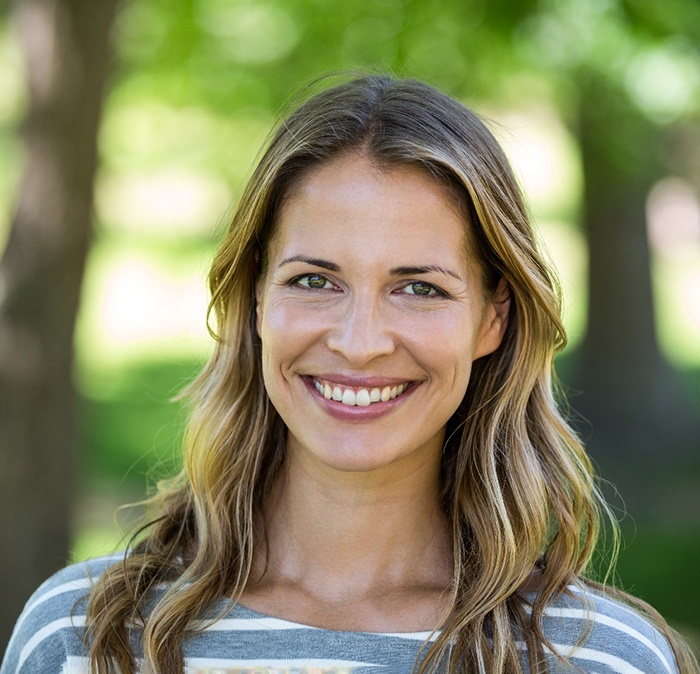 Woman in striped shirt standing outside smiling