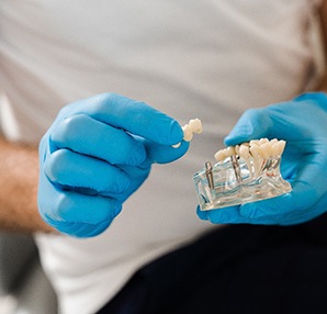 Dentist showing patient model of dental implants in Houston, TX