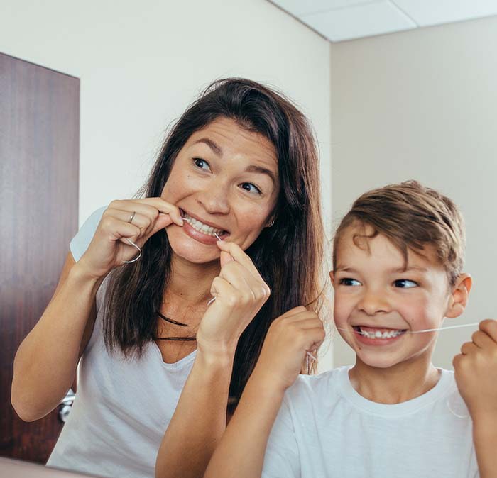 Mother and son flossing to prevent toothache in Houston