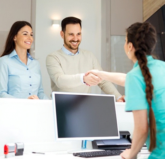 dental receptionist shaking a patient’s hand