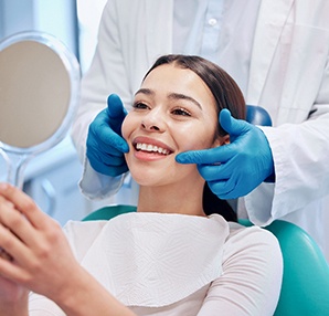 a smiling patient looking into a handheld mirror