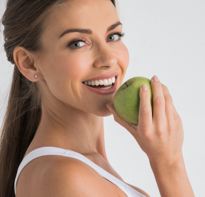 Woman eating an apple after dental implant tooth replacement