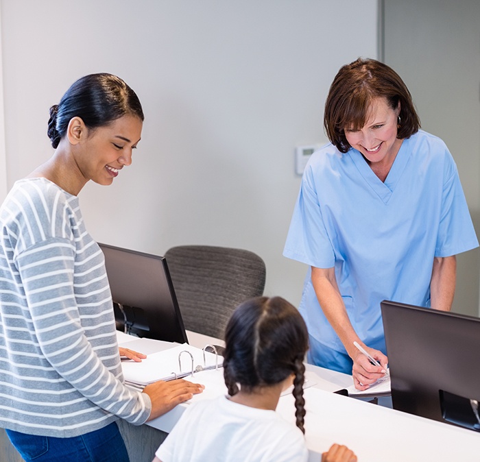 Mother and child giving team member dental insurance information