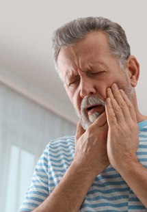 a man touching his cheek due to tooth pain