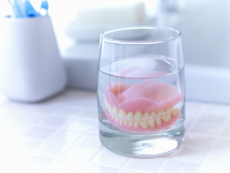 set of dentures in a glass of water